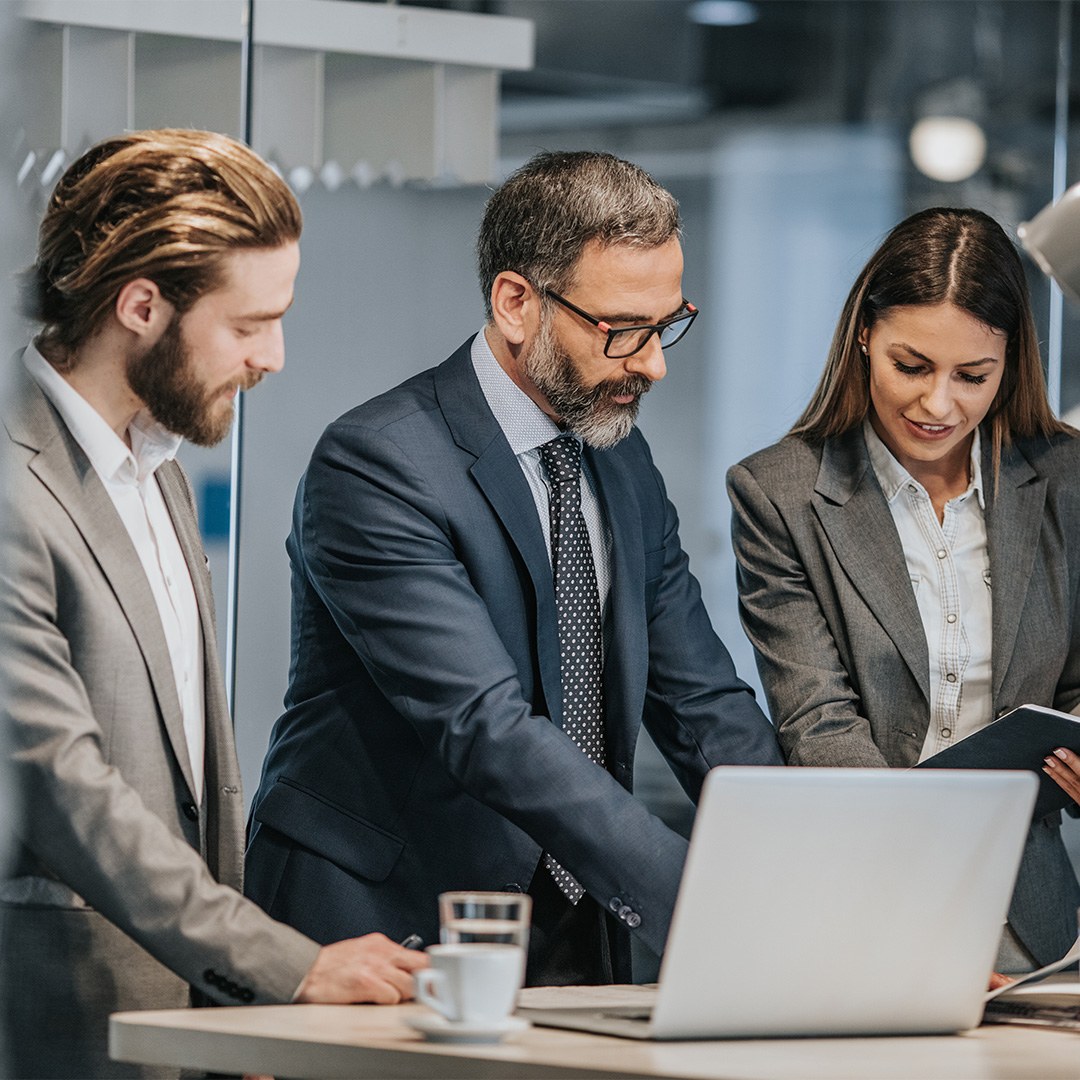 A group of three people circled around a computer