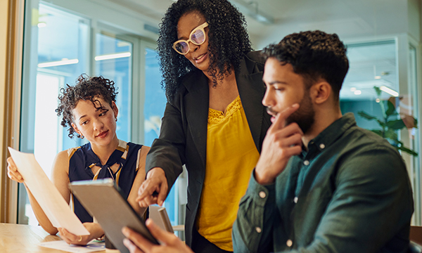 A group of three individuals starring at a screen discussing a topic
