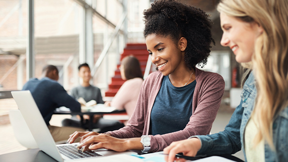 Two female students collaborating around a computer