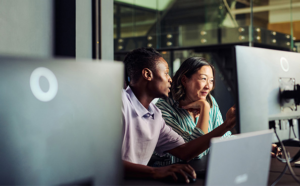 Two people talking together in front of a computer