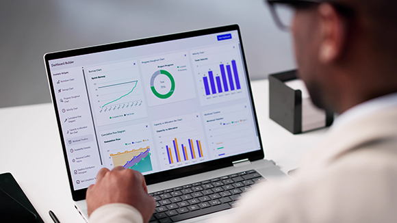 A man looking at a computer that is displaying different type of graphs
